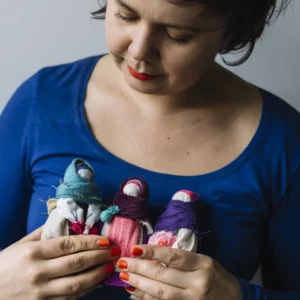 Kasia Dorota trzyma w ręki trzy Podróżki, motanki