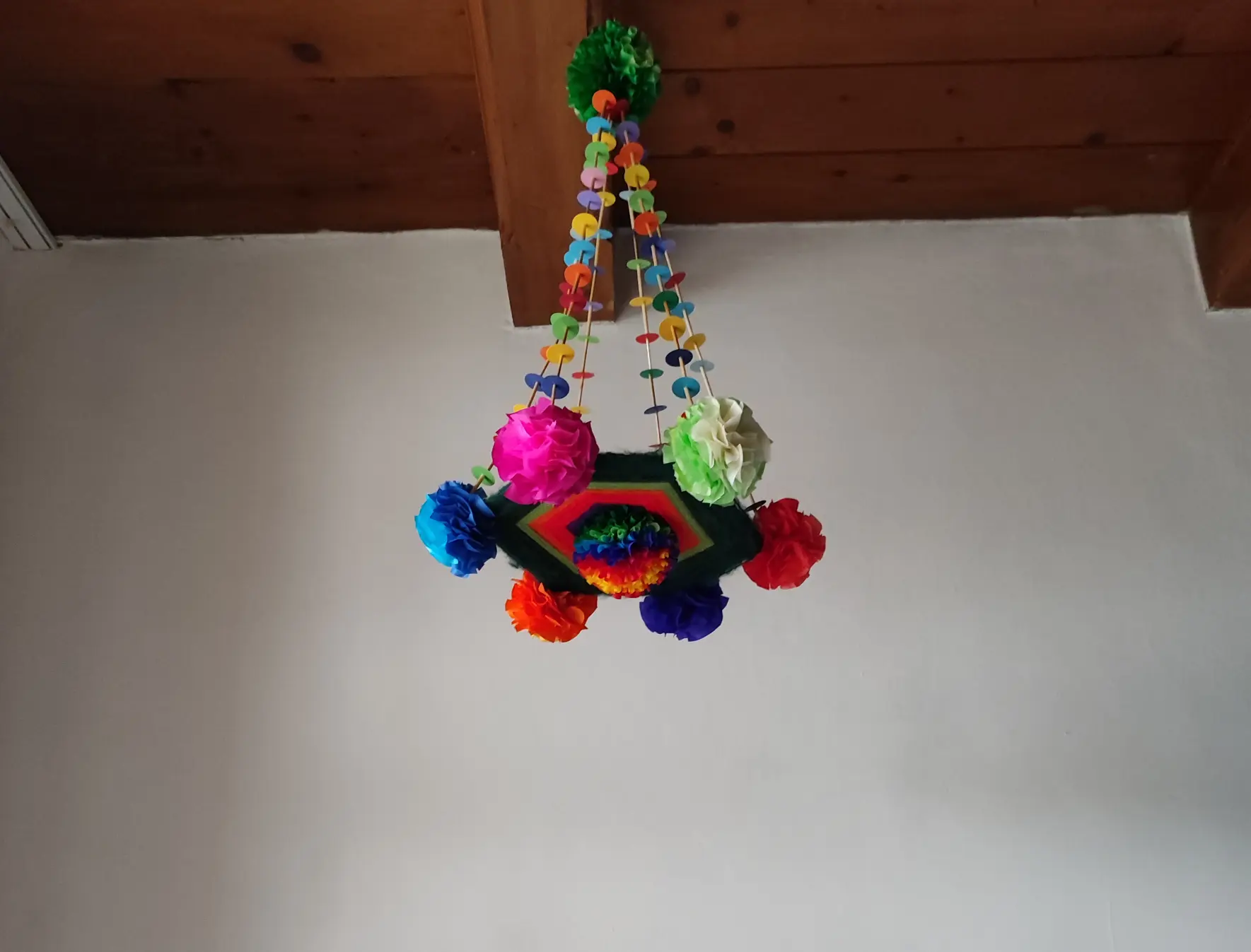 pająk wykonany na tarczy wytkanej kolorowymi nićmi i włóczkami, ozdobiony kalinkami czyli ozdobami z kolorowych bibuł