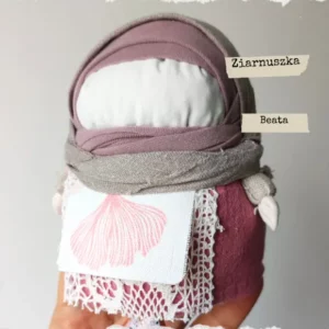 Tradycyjna Motanka, wykonana z tkaniny i wypełniona ziarnami. Ma pękaty kształt i kolorowe ubranie - chustkę na głowie, sukienkę i fartuszek. Jest jedną z największych motanek.