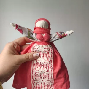 Motanka, tradycyjna lalka mocy, w kolorach brzoskwiniowych, z koronkowym fartuszkiem.