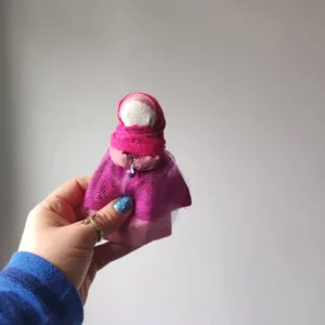 Lalka motanka wykonana z kawałków tkanin i nici. Motanka ma na sobie ubranie w kolorze różowym