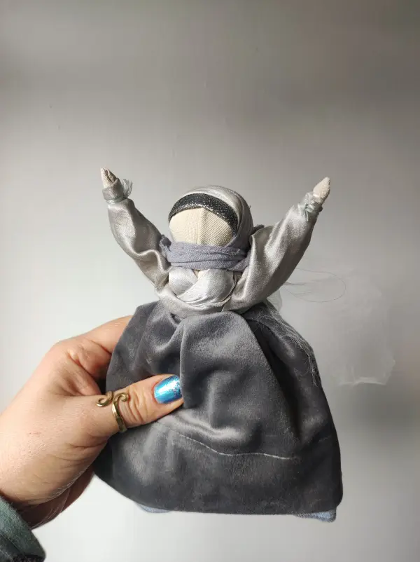 Lalka zamotana z tkanin i nici w kolorze srebrnym.