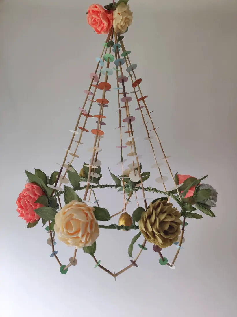 Pająk obręczowy wykonany na obręczy metalowej, ozdobiony kurpiowskimi różami z krepiny, kolorowych papierów, słomek oraz z powieszonym w centrum złotą pisanką.